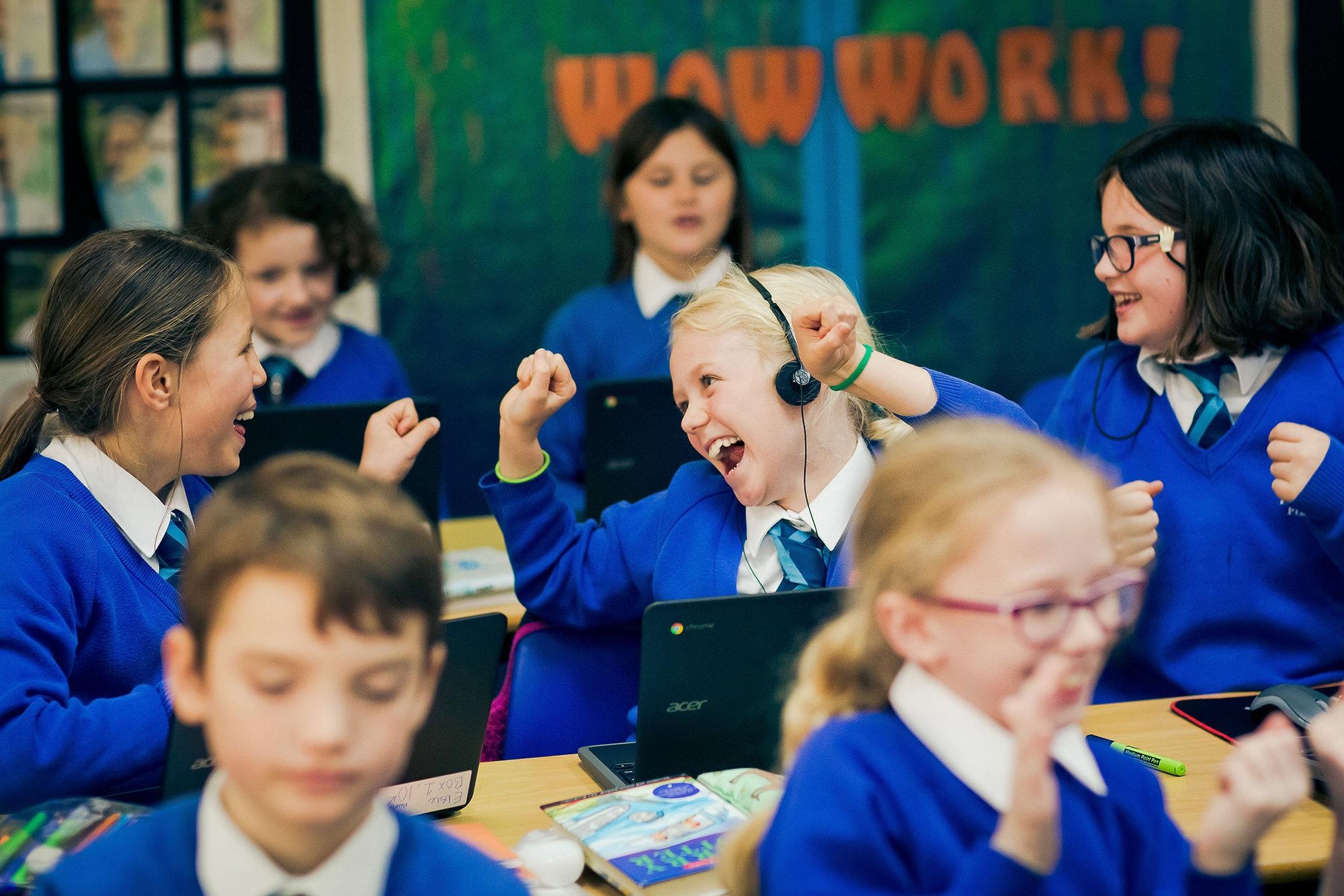 Children smiling while working on laptops